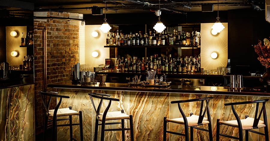 A lit bar setting tiled with onyx emerald polished porcelain wall tiles